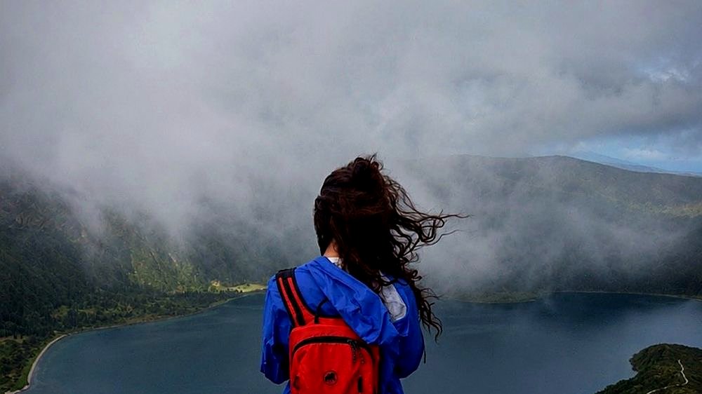 Hiker overlooking Lagoa do Fogo volcanic lake with mist, São Miguel Island, Azores